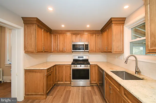 a kitchen with granite countertop wooden cabinets a stove top oven and stainless steel appliances