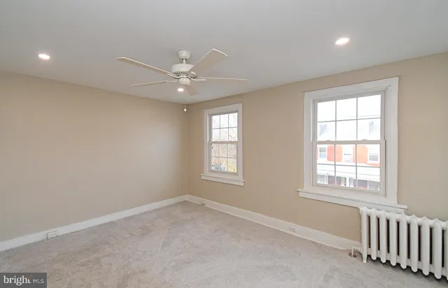 an empty room with windows and fan