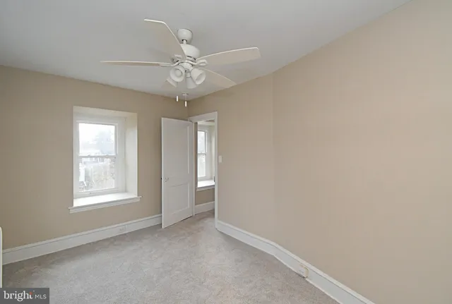 an empty room with windows and fan