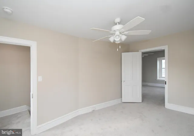 an empty room with a ceiling fan and a window