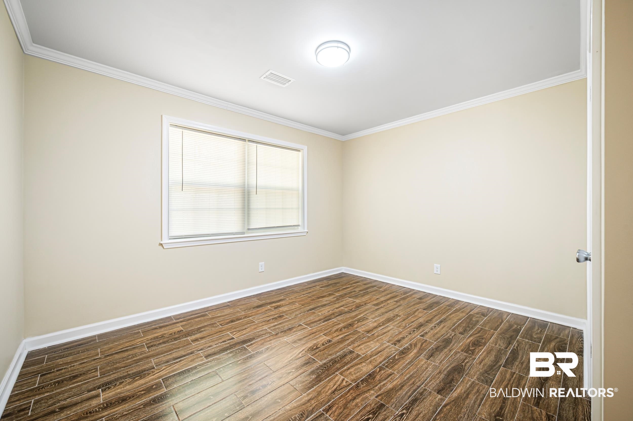 1605 Collier Avenue Bay Minette, AL 36507 - Photo 17 of 36 Empty room with crown molding and wood tiled floors