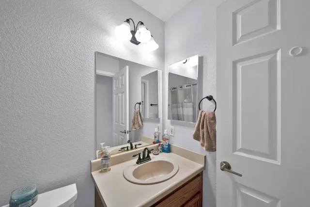 a bathroom with a granite countertop sink and a refrigerator