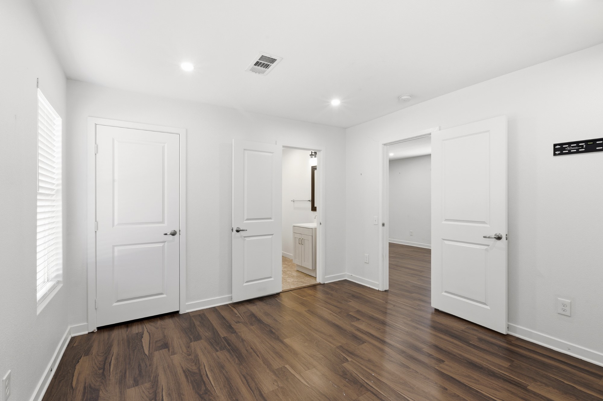 108 Irene Street Elgin, TX 78621 - Photo 15 of 29 Unfurnished bedroom with multiple windows, ensuite bath, dark wood finished floors, and recessed lighting