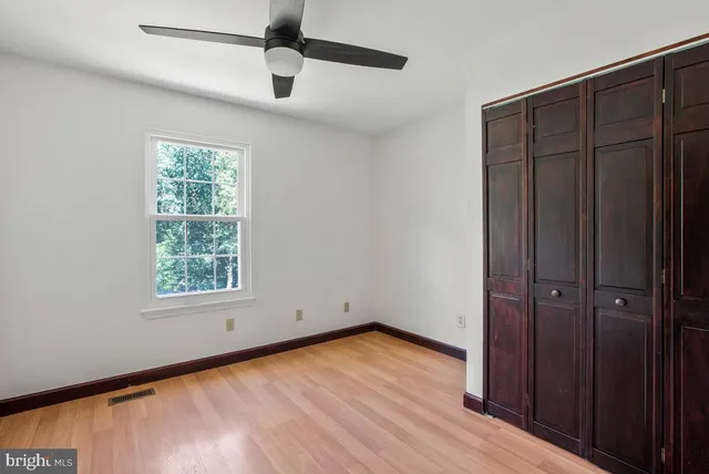 an empty room with wooden floor closet and windows