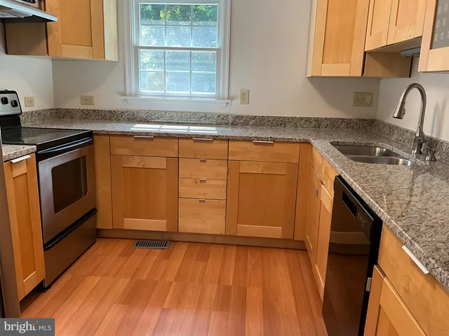 a kitchen with granite countertop wooden cabinets a sink and dishwasher