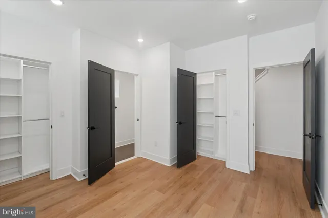 a view of an empty room with wooden floor and closet area