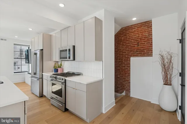 a kitchen with stainless steel appliances white cabinets and wooden floor