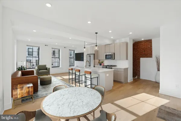 a living room with stainless steel appliances kitchen island granite countertop a dining table chairs and a kitchen view