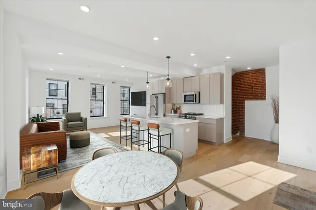 a living room with stainless steel appliances kitchen island granite countertop a dining table chairs and a kitchen view