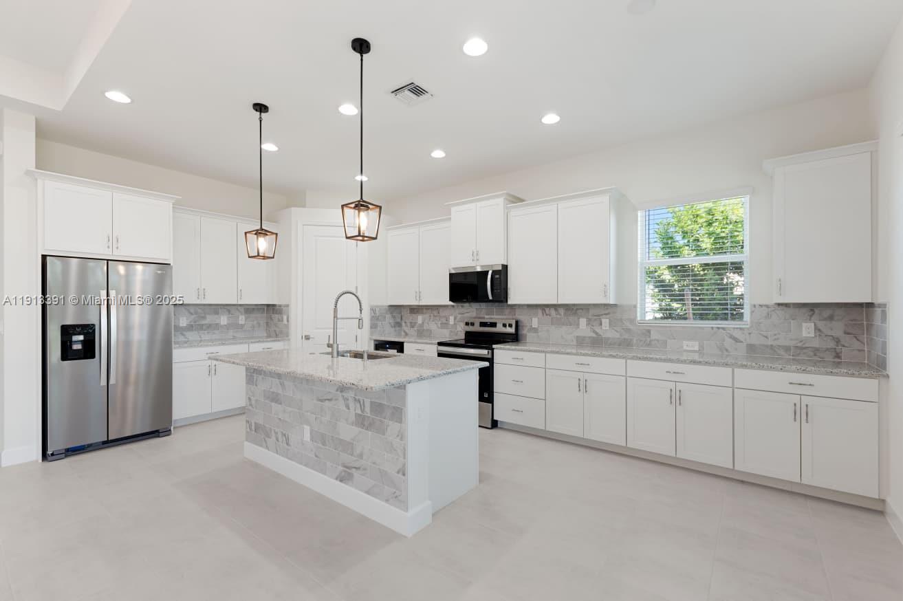 5786 Aleppo Pne Place Westlake, FL 33470 - Photo 6 of 30 a large kitchen with stainless steel appliances kitchen island granite countertop a sink a stove and a refrigerator
