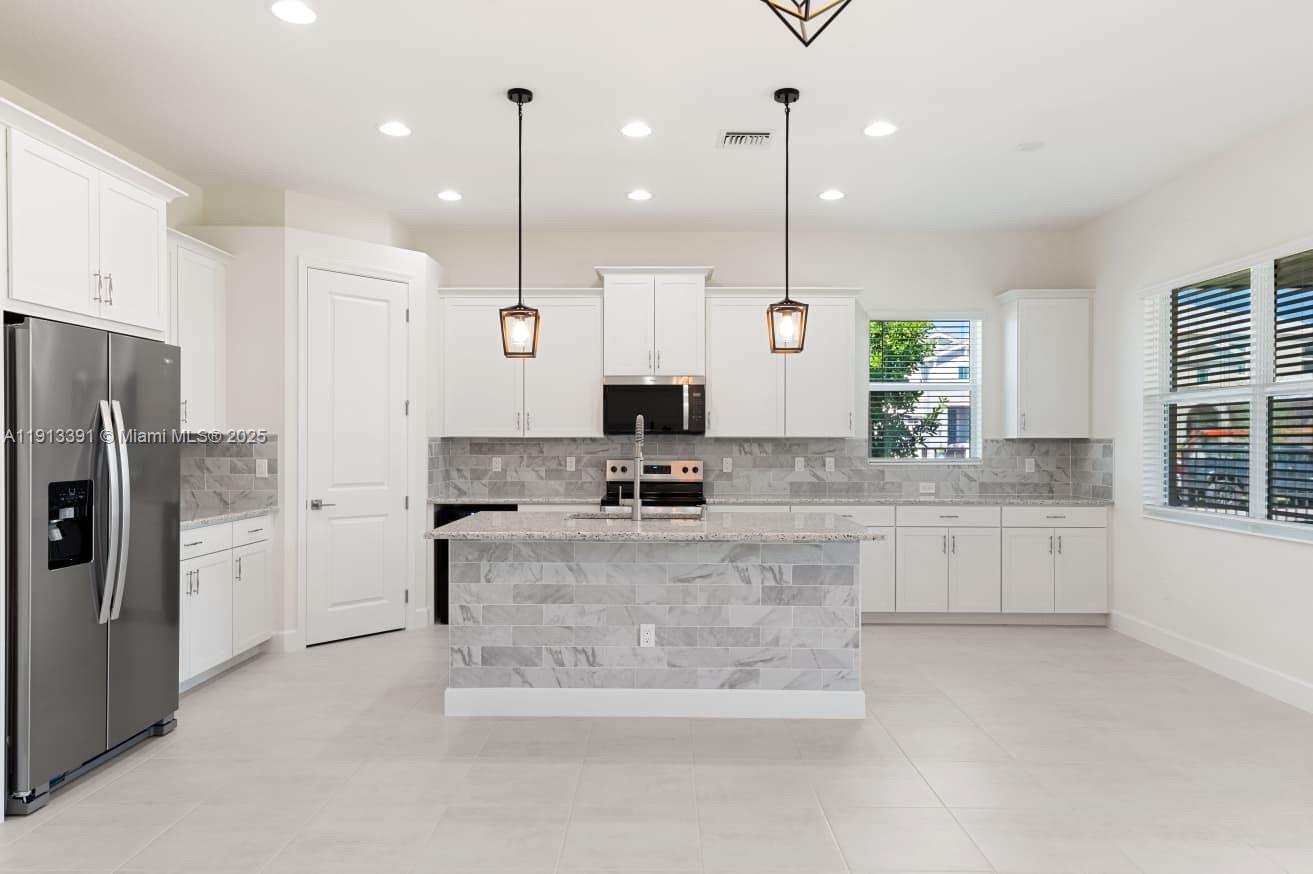 5786 Aleppo Pne Place Westlake, FL 33470 - Photo 7 of 30 a large kitchen with stainless steel appliances kitchen island granite countertop a refrigerator a oven and a white cabinets