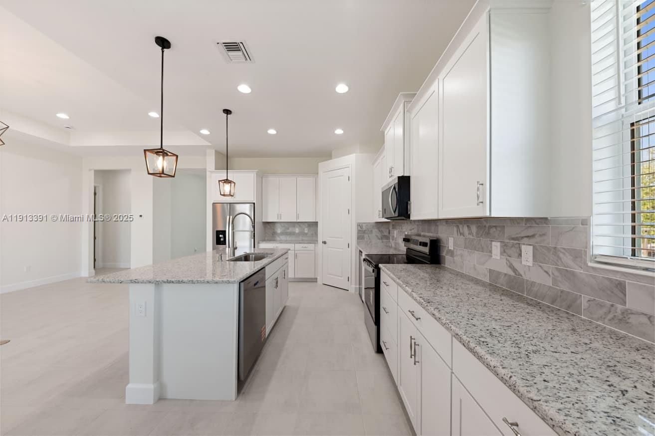 5786 Aleppo Pne Place Westlake, FL 33470 - Photo 9 of 30 a large kitchen with stainless steel appliances kitchen island granite countertop a sink and cabinets