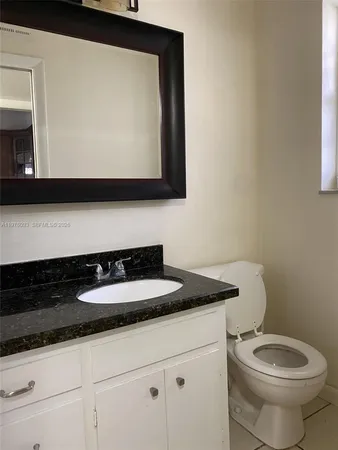 a bathroom with a granite countertop toilet sink and mirror
