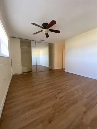 a view of empty room with wooden floor and fan
