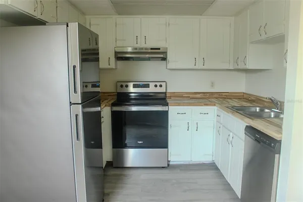 an empty room with wooden floor cabinet and windows
