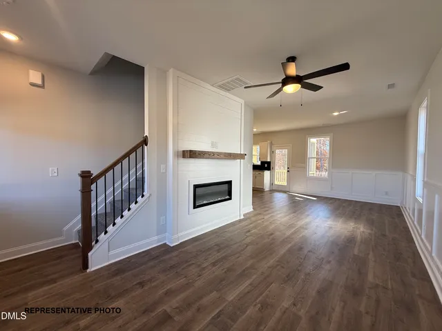a view of a livingroom with wooden floor a ceiling fan and kitchen space