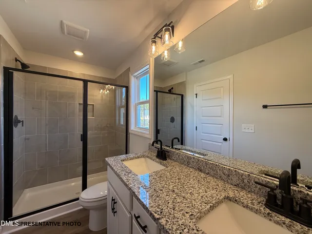 a bathroom with a granite countertop sink a toilet a mirror and shower
