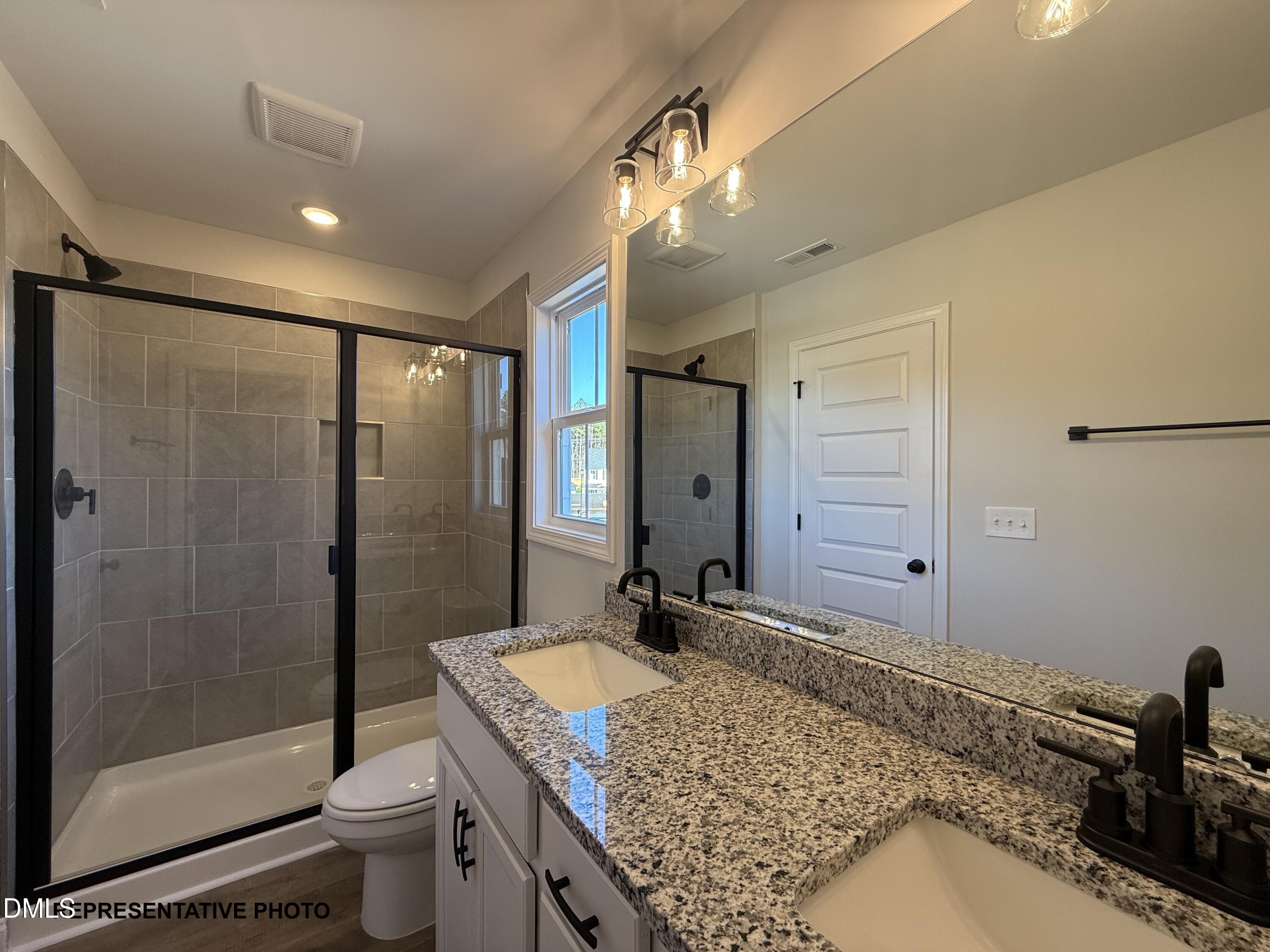 308 Bluejay Street Clayton, NC 27520 - Photo 6 of 14 a bathroom with a granite countertop sink a toilet a mirror and shower