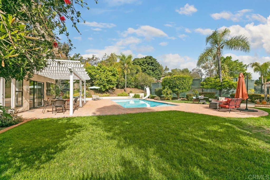 a view of pool with lawn chairs and large trees