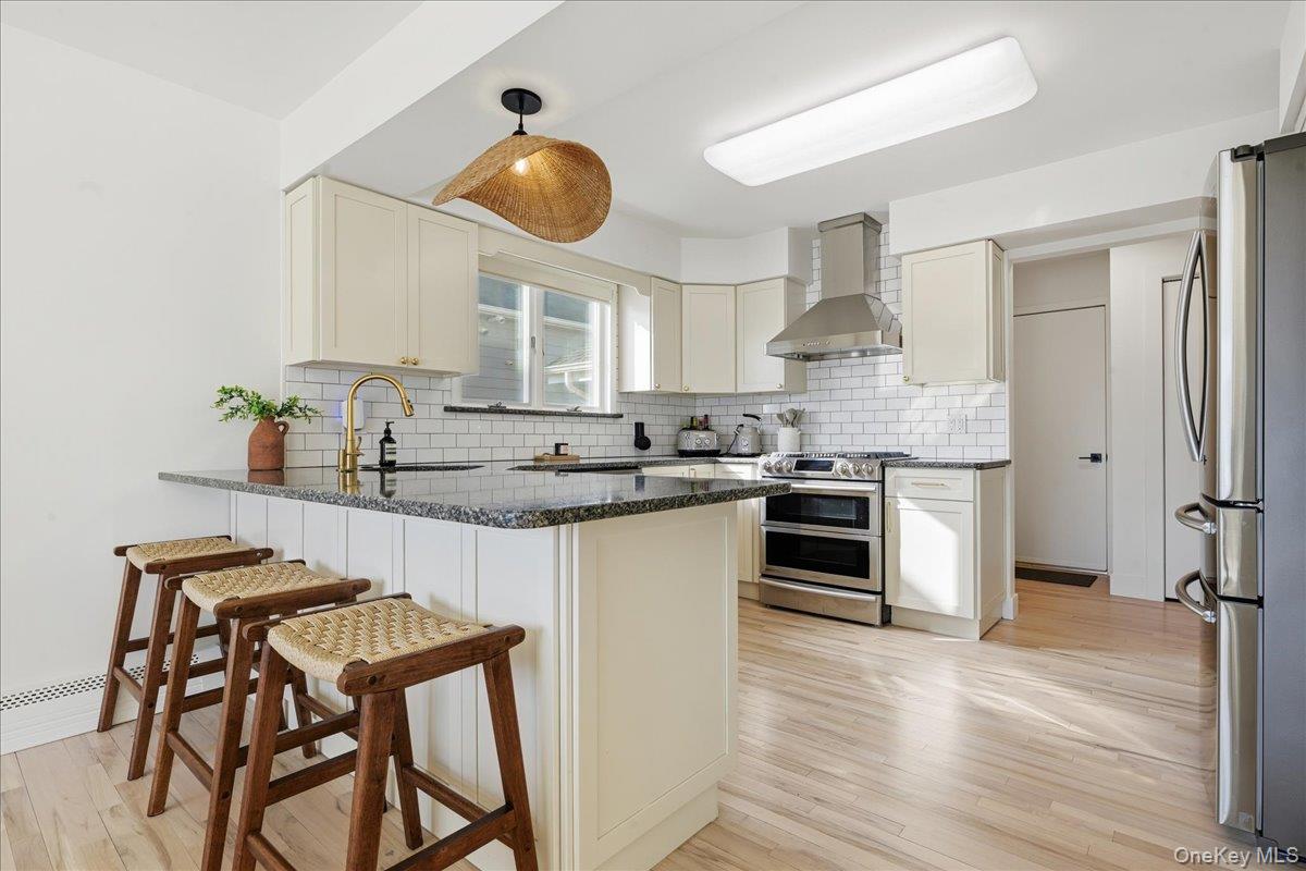141 Annuskemunnica Road Babylon, NY 11702 - Photo 6 of 44 a kitchen with stainless steel appliances granite countertop a stove top oven a refrigerator a sink and dishwasher with wooden floor