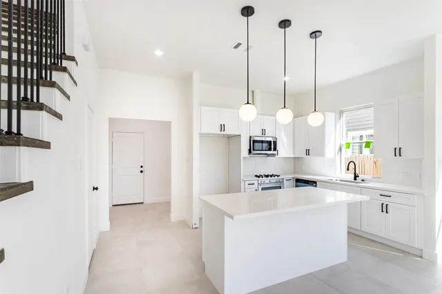 a kitchen with kitchen island a sink a center island a stove and a window