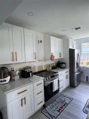 a kitchen with stainless steel appliances granite countertop a sink stove refrigerator and cabinets