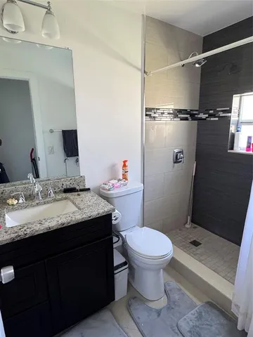 a bathroom with a granite countertop sink toilet and shower
