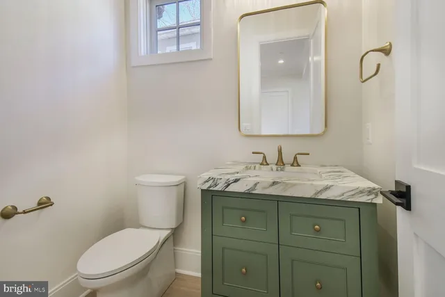 a bathroom with a granite countertop toilet sink and mirror