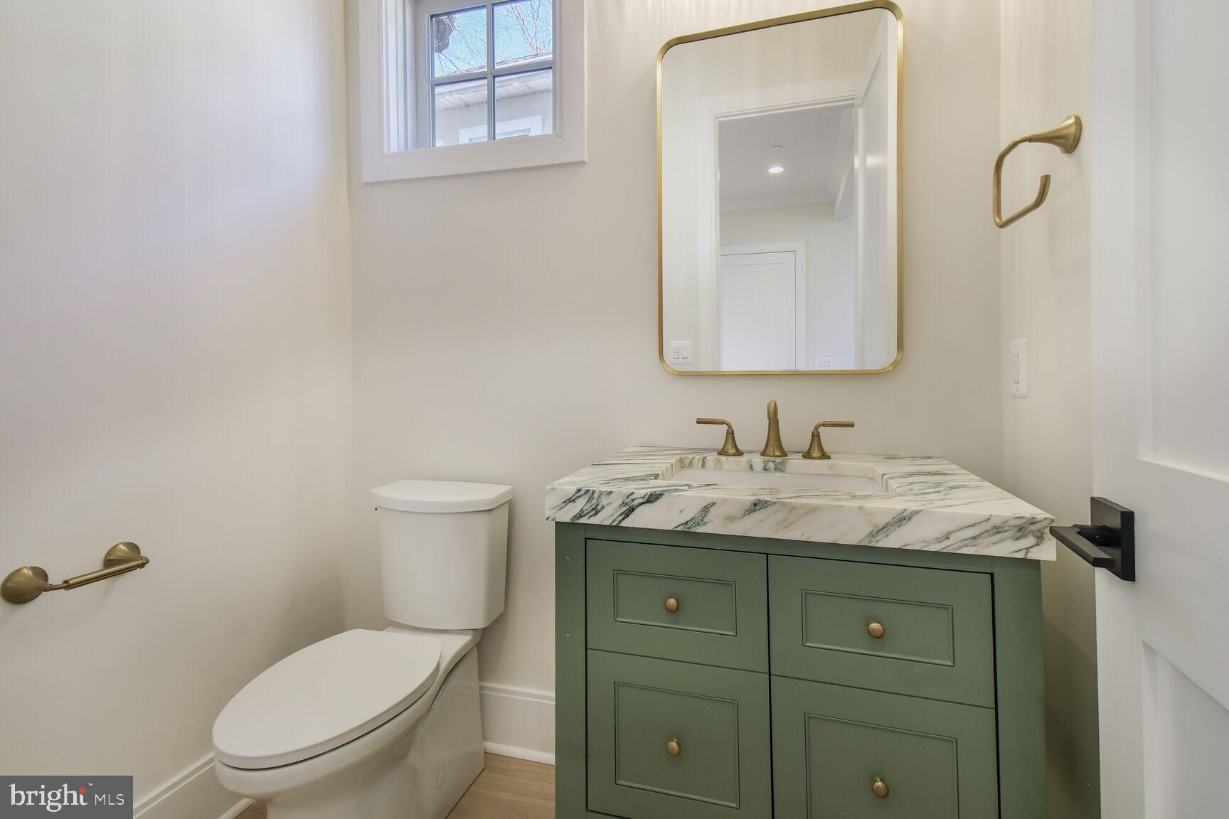 7819 Exeter Road Bethesda, MD 20814 - Photo 17 of 44 a bathroom with a granite countertop toilet sink and mirror
