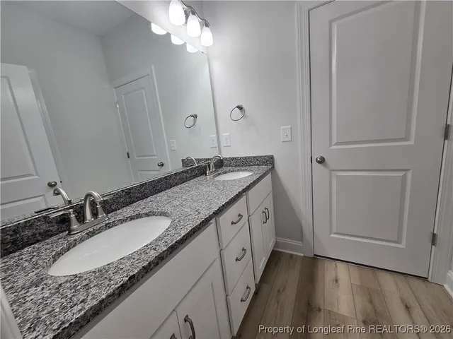 a bathroom with a granite countertop double vanity sink and a mirror