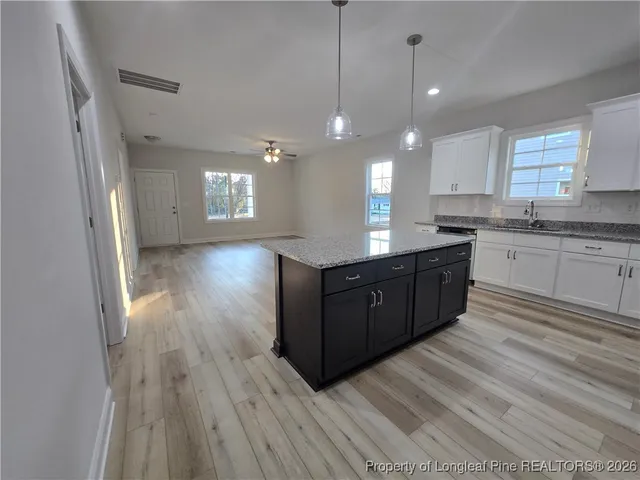 a large kitchen with granite countertop a large counter top space a sink stainless steel appliances and cabinets