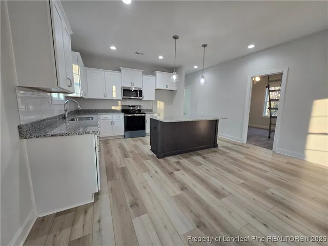 a large kitchen with stainless steel appliances granite countertop a stove a sink and a refrigerator