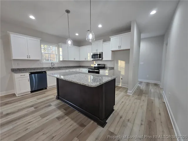 a kitchen with kitchen island granite countertop a sink cabinets and wooden floor