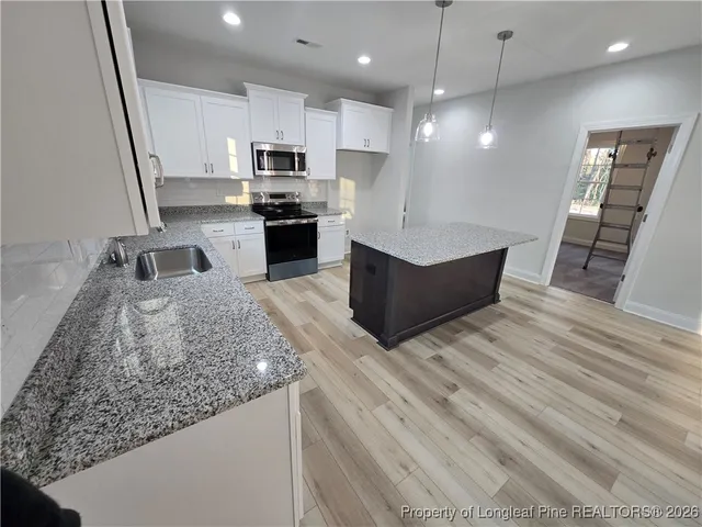 a large kitchen with stainless steel appliances kitchen island granite countertop a sink counter space and cabinets