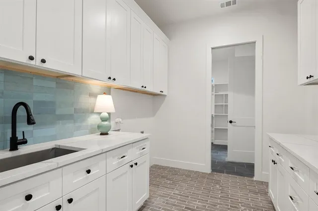 a kitchen with white cabinets and sink