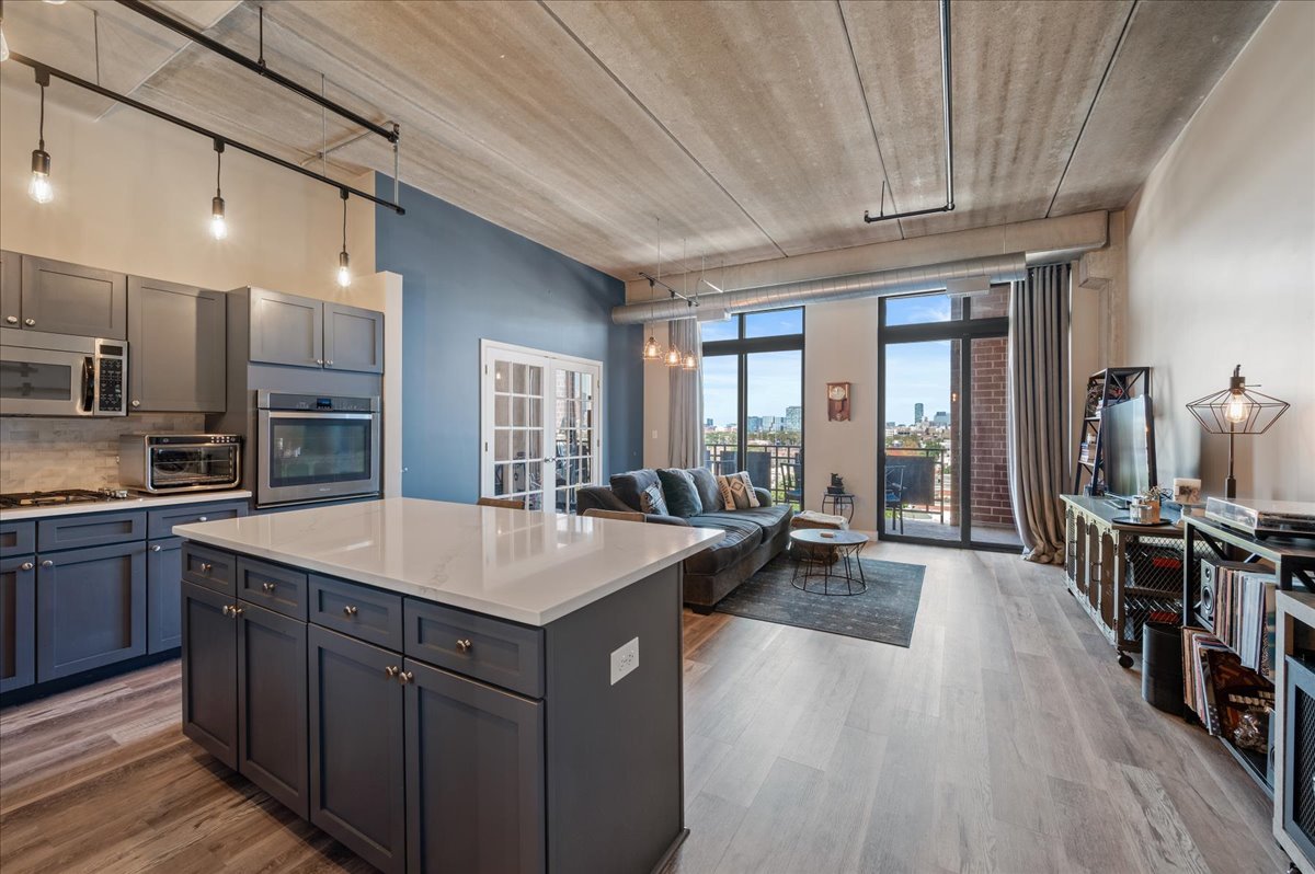 811 West 15th Place, Unit 708 Chicago, IL 60608 - Photo 7 of 26 a kitchen with kitchen island granite countertop a sink stove and wooden floor