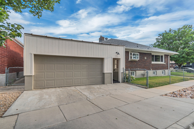 4883 South Center Street Murray, UT 84107 - Photo 31 of 32 Attached 2-car garage with panel siding, an overhead door, and a dedicated pedestrian entry