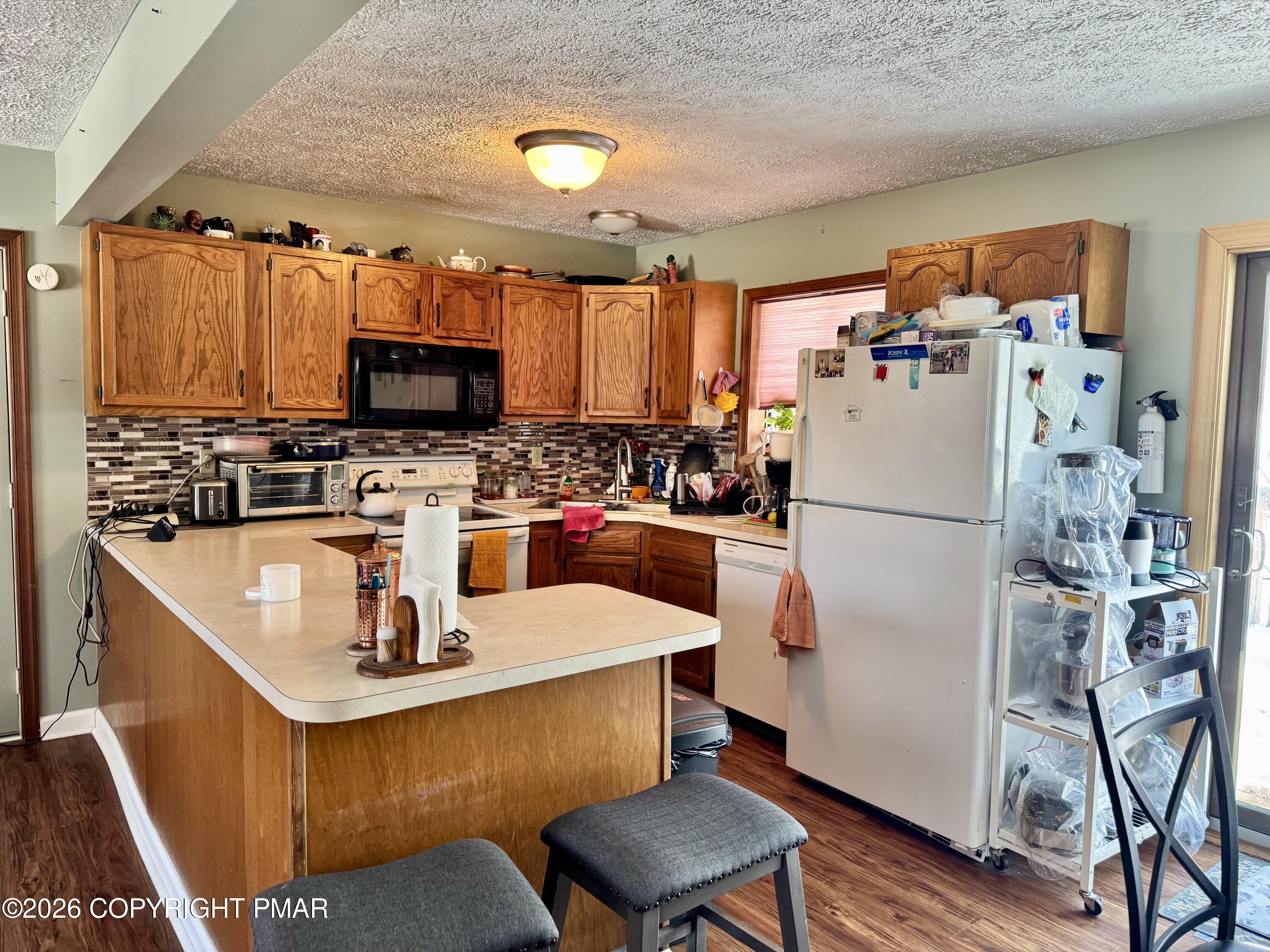 217 Bindale Road Tamiment, PA 18371 - Photo 6 of 27 a kitchen with a refrigerator a stove a sink dishwasher and a microwave oven with wooden floor