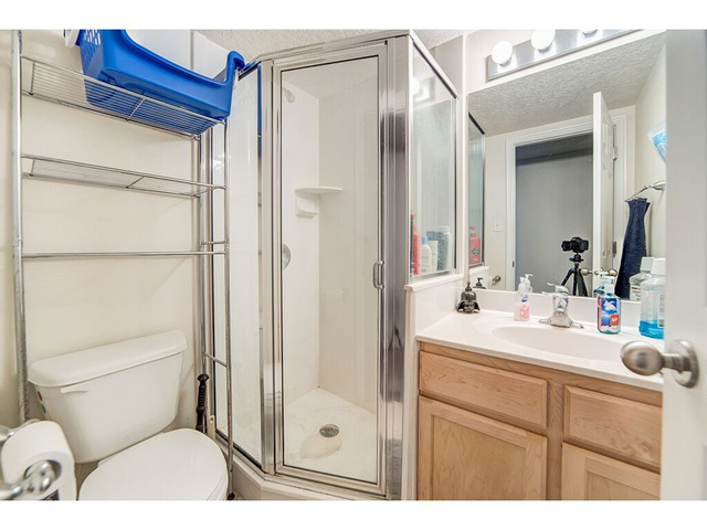 865 North 500 West, Unit 5 Provo, UT 84604 - Photo 5 of 14 Bathroom featuring a glass-enclosed shower, single vanity with a light-toned countertop, natural wood-finish cabinetry, and contemporary vanity lighting