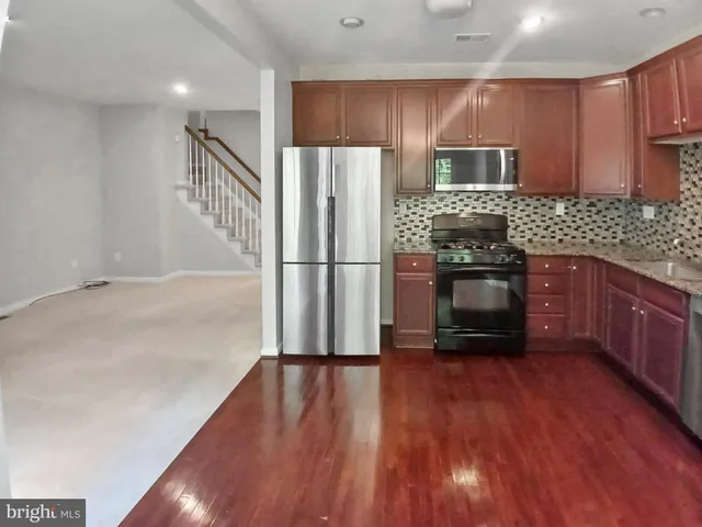 a kitchen with stainless steel appliances wooden floor wooden cabinets and a wooden floor
