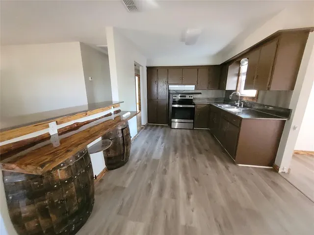 a kitchen with stainless steel appliances wooden floor sink stove microwave and cabinets