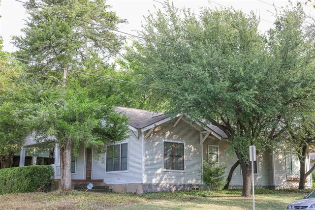 a front view of a house with a garden and trees