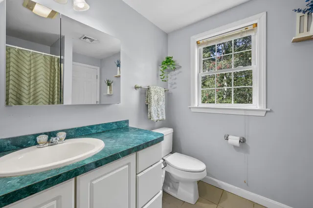 a bathroom with a granite countertop sink toilet and mirror