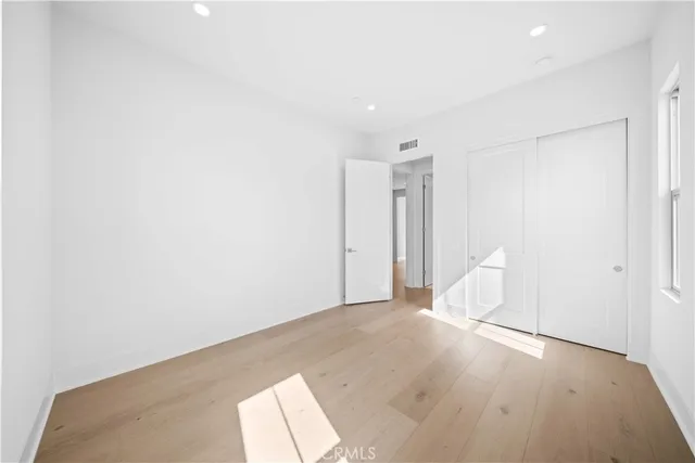 a view of an empty room with a window and kitchen view