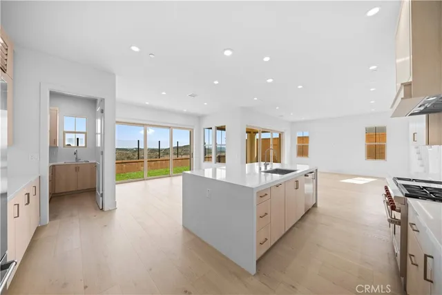 a large white kitchen with kitchen island a sink a stove and a refrigerator