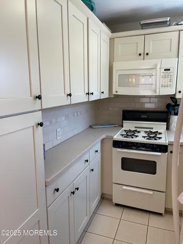 a kitchen with granite countertop white cabinets and white appliances