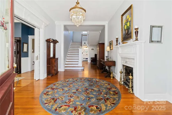 a view of a livingroom with furniture a fireplace wooden floor and chandelier