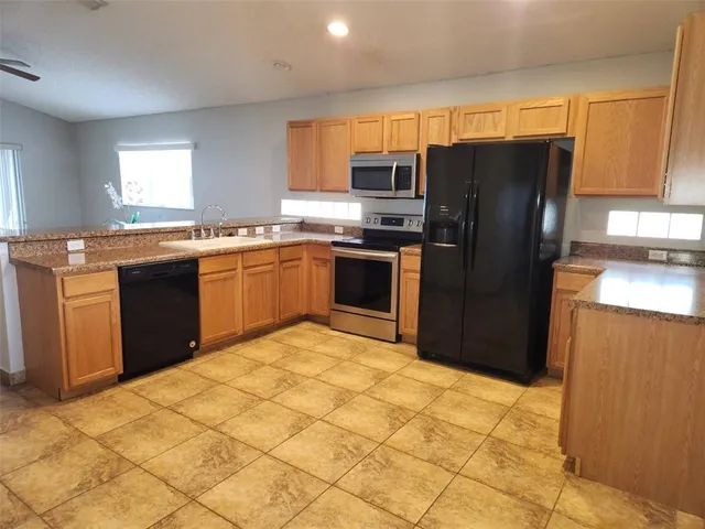 a kitchen with stainless steel appliances granite countertop a refrigerator stove top oven and sink