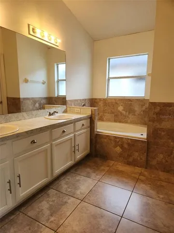 a bathroom with a granite countertop sink a mirror and a bathtub
