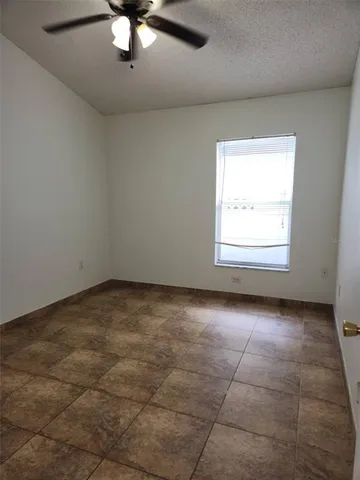 an empty room with a ceiling fan and window
